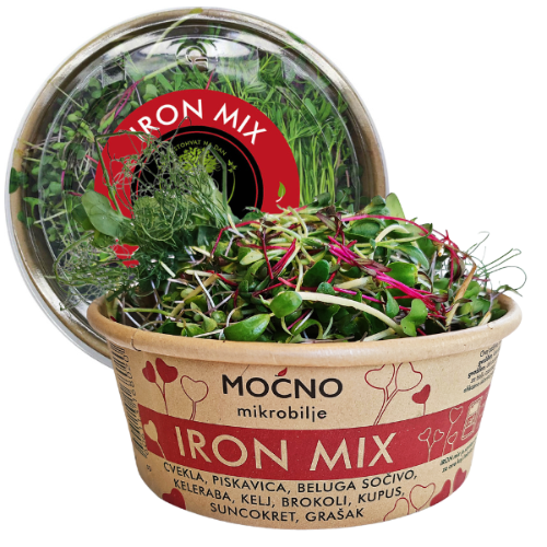 Central view of the MOĆNO Iron Mix packaging. Red label on the lid leaning against a bowl full of fresh beetroot, lentil, and wheat microgreens.
