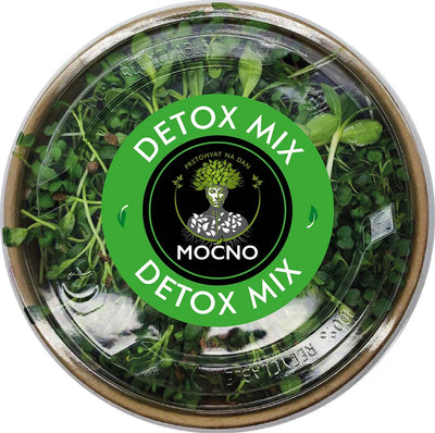 Shot of the Detox Mix lid from above. The green label design with the MOĆNO logo and clearly written ingredients dominates: broccoli, kale, cabbage, wheat, fenugreek, mustard, pak choi, and sunflower.