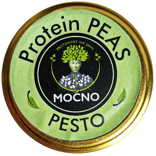 Kadar poklopca tegle odozgo. U fokusu je kružna svetlozelena etiketa sa MOĆNO logotipom i nazivom "Protein Peas Pesto", koja vizuelno odvaja ovaj ukus od ostalih namaza u asortimanu.