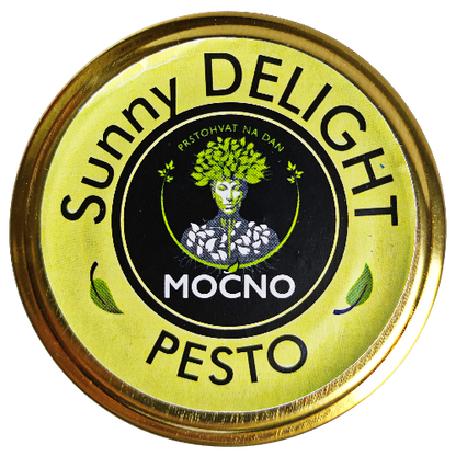 Kadar poklopca tegle odozgo. U fokusu je žuta kružna etiketa sa MOĆNO logotipom i nazivom "Sunny Delight Pesto", koja simbolizuje energiju sunca i bogatstvo magnezijuma.
