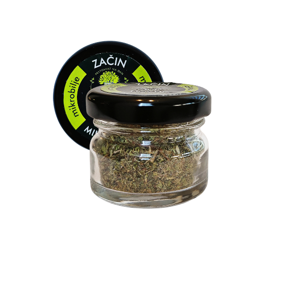 Centralni prikaz male staklene teglice MOĆNO sušenog Basic začina. Jasno vidljiva crna etiketa sa belim i zelenim detaljima, dok se kroz staklo vidi fino usitnjeno sušeno mikrobilje.